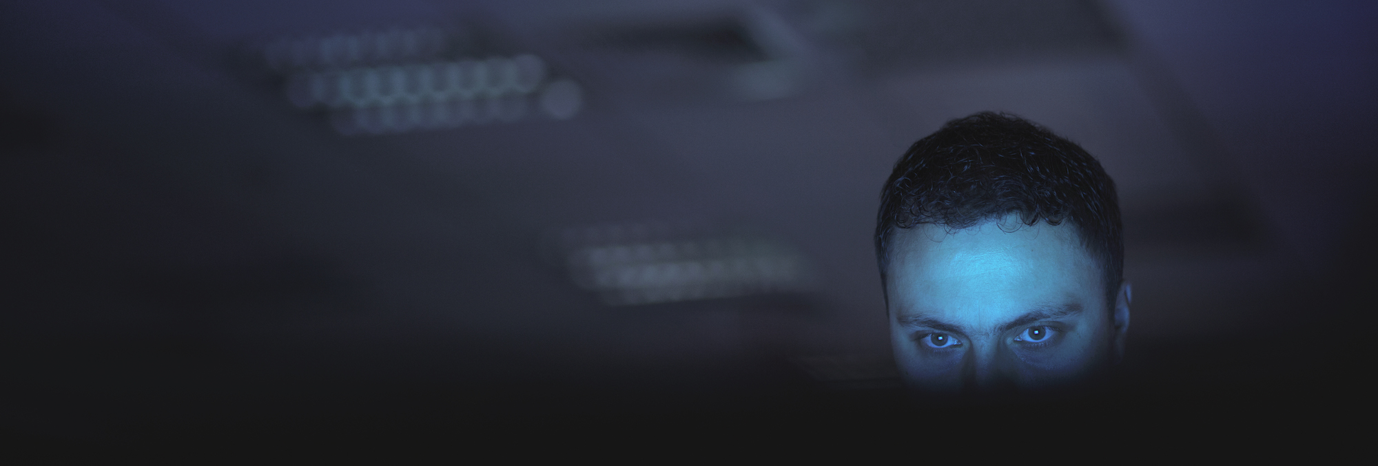 Computer hacker working on laptop late at night in office