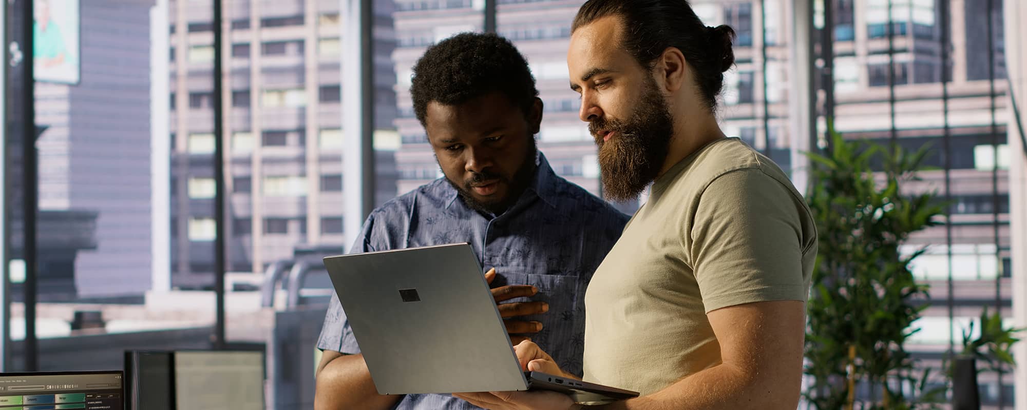Two IT professionals looking at a a laptop screen with buildings in the background